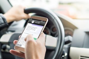 A man types a text message while driving.