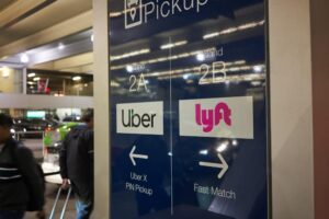 Rideshare Accident Lawyer in Savannah | 24/7 Help A sign has both the Uber and Lyft logos with arrows showing where pick-up areas are.