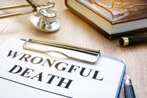 A document that says “wrongful death” lies on a table near a stethoscope, a book, and some pens.