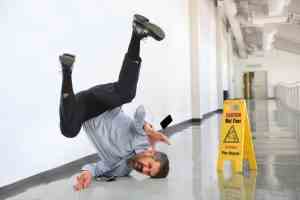 A man slips and falls hurting himself near a wet floor sign.