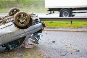 Warner Robins Rollover Accident Lawyers | Free Consultations Available A car lies on the highway rolled over with extensive damages.