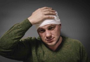Mableton Head Injury Lawyers | Free Case Reviews | Support 24/7 A man holds his bandaged head with his hand.