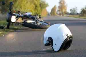 A helmet lies by a crashed motorcycle.