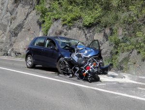 The aftermath of a motorcycle accident that occurred on the road. There is massive damage to the fronts of both vehicles.