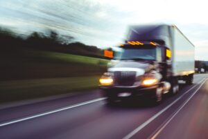 Mableton 18-Wheeler Accident Lawyer | Get Help with Your Claim Today A large 18-wheeler drives fast on the road at dusk.