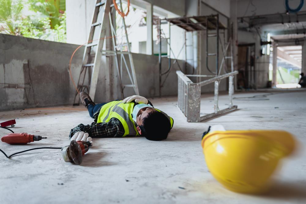A construction worker who fell off a ladder holds his injured leg in pain.