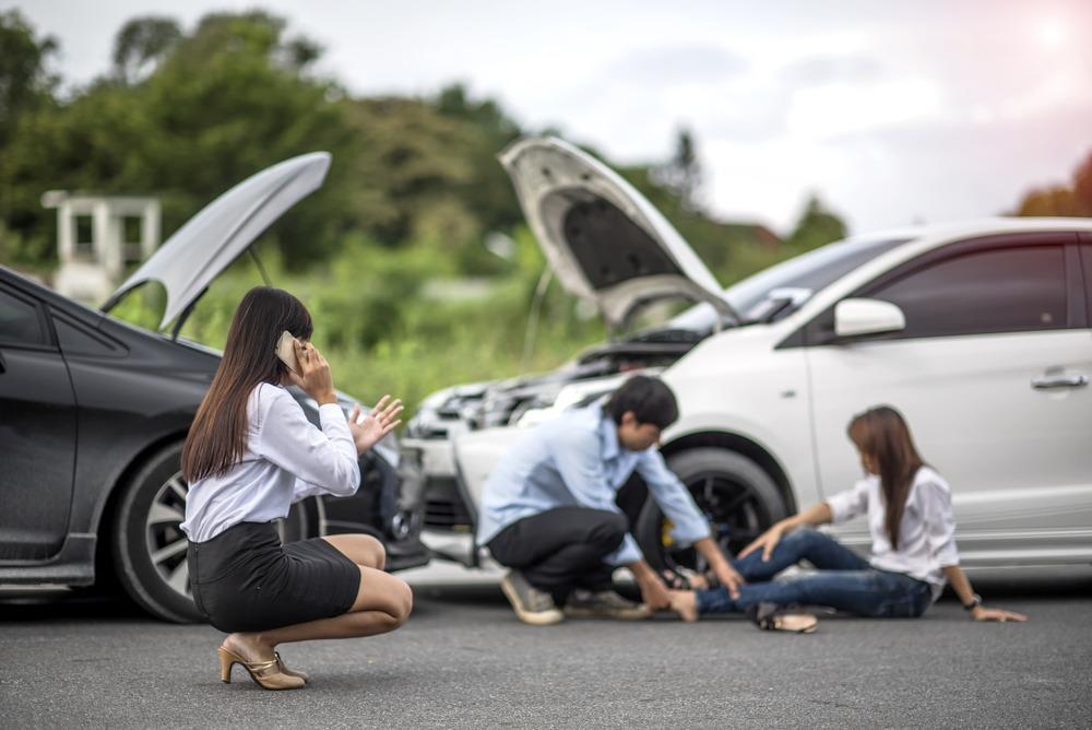 woman calling for help while another individual tends to injured person 