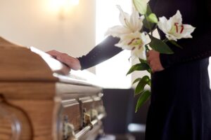 Columbus, GA, Wrongful Death Lawyer | Free Consultations A woman holds flowers while touching a coffin.
