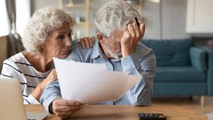 An elderly couple worries over paperwork.
