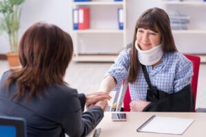 Atlanta Personal Injury Lawyer | No Upfront Fees | 24/7 Support A lawyer shakes hands with an injured client wearing an arm sling and neck brace.