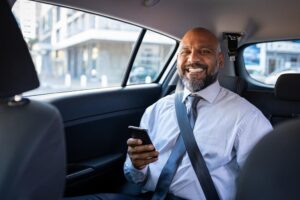 Stockbridge Lyft Accident Lawyers | John Foy | No Upfront Fees man in back seat of car holding phone and smiling
