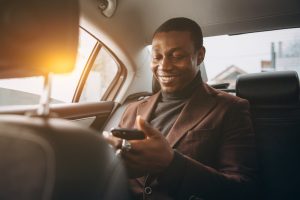 man rides in back seat of car using phone