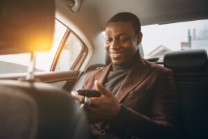 Union City Lyft Accident Lawyers | John Foy | 24/7 Support man rides in back seat of car using phone