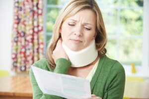 Rear-End Collision Lawyer in Doraville | John Foy & Associates woman in neck brace deals with bills