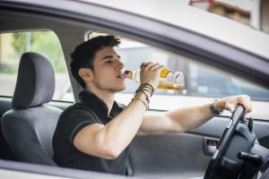 teenage guy drinking behind the wheel
