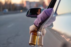 Drunk Driving Accident Lawyer in Statesboro guy holding bottle of beer out window