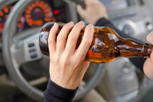 person drinking a beer while driving