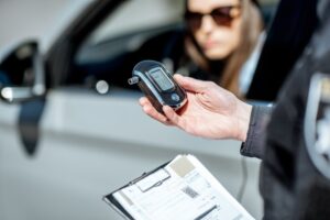 Drunk Driving Accident Lawyer in Peachtree Corners cop checking breathalyzer for drunk driver