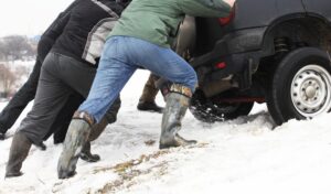 people pushing a car out of snow