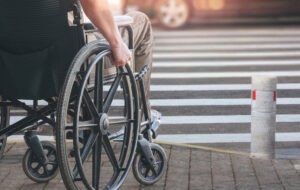 man in wheelchair waiting to cross the street