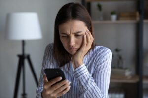 woman stressfully looking at her phone