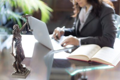 Lawyer in office with statue of justice scales while working