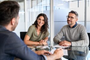 A happy couple sits with a lawyer, wondering what to consider when choosing a lawyer.