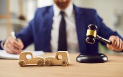 Do I Need an Attorney for an Uber Accident Claim? | John Foy A car accident lawyer sits at a desk in front of two toy cars getting in a crash. Do I need a lawyer for an Uber accident claim?