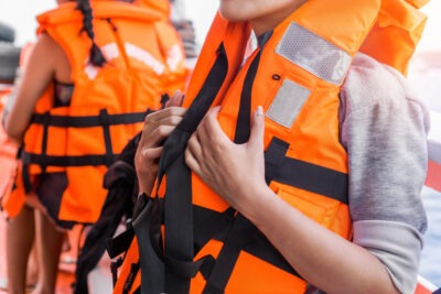 How Common are Passenger and Crew Deaths on Cruises? A woman in a life jacket on a cruise ship wonders, “How common are passenger and crew deaths on cruise ships?”