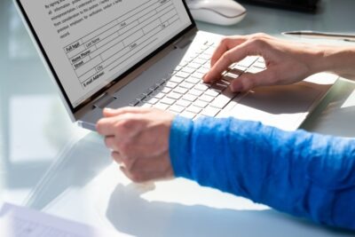 How to Beat a Workers’ Comp Adjuster's Strategies | John Foy A man with a broken arm fills out a workers’ comp form. He wonders about the games workers’ comp adjusters play and how to beat them.