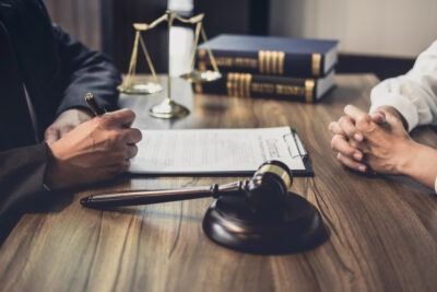 How Many Hours Can I Work While on SSDI? Lawyer sits at desk with client and explains how many hours they can work while on SSDI.