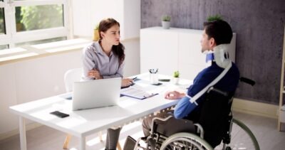 How Does Maritime Law Impact Cruise Ship Injury Lawsuits? Man in a wheelchair and dealing with injuries after traveling on a cruise ship speaking with a lawyer about how maritime law impacts cruise ship injury lawsuits.
