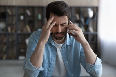 How Do I Negotiate a Settlement With The General Insurance? A stressed man on a phone call. Learn how to negotiate a settlement with The General Insurance.