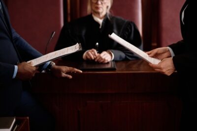 What Is the Workers' Comp Hearing Process in Georgia? Two attorneys compare notes as a judge presides over the workers’ compensation hearing process in Georgia