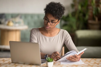 A woman using her computer to research whether State Farm offers accident forgiveness.