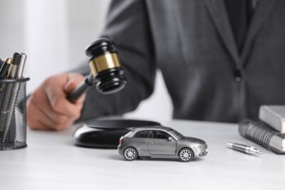 A car accident lawyer has a toy car and a gavel at his desk. He can explain what it means when a car accident claim goes to arbitration.