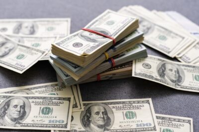 A pile of dollar bills on a table, with someone nearby wondering how much money may be available to them through SSDI