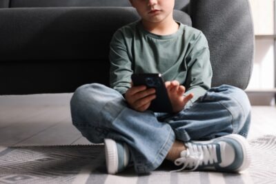 A boy using a smartphone. Learn about what’s happening with social media addiction lawsuits.